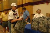 A junior competitor takes a National Guard backpack at tournament registration.