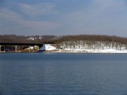 Morning sunlight illuminates the whitened face of a hill on the west end of the Hwy. 62 Bridge across Norfolk Lake.