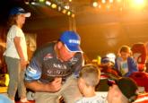Pro Alton Jones signs autographs for fans after the final Kentucky Lake weigh-in while his own children hang out in the boat.