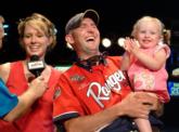 Co-angler champion Aaron McManaway laughs while his daughter claps and his wife talks to host Charlie Evans.