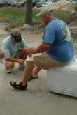 Tournament director Dan Grimes administers first aid to One Flipper Capt. Ed Langel after a kingfish took a bite of his toe.