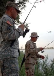 CAMP VICTORY, Iraq -- U.S. Army Staff Sgt. Bill Benson, left, eyes a possible catch by U.S. Air Force Master Sgt. Rodney Scott during the Z-Lake Fishing Tournament here Oct. 20. The 169th Cargo Transfer Co. NCO and 447th Expeditionary Logistics Readiness Squadron Aerial Port Passenger Service manager were two of about a dozen servicemembers vying for the biggest catch of the day. 