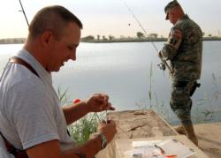 CAMP VICTORY, Iraq -- U.S. Air Force Chief Master Sgt. Lance Endee, left, and Master Sgt. Larry Goulden, 447th Expeditionary Security Forces Squadron, prep their lines for the Z-Lake Fishing Tournament here Oct. 20. 