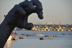 A giant hand from The Awakening frames National Harbor marina during takeoff. The statue, created by J. Seward Johnson, Jr. and originally installed at Hains Point in Washington, D.C. in 1980, was moved to the National Harbor in 2007 after the artist sold the statue for $750,000.
